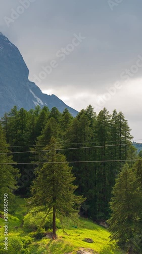Matterhorn mountain peak time lapse with passing cable car and moving clouds over green alpine pine forest in Zermatt Switzerland