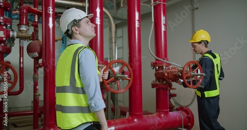 Obraz na plátně Two engineers conduct a detailed inspection of an industrial fire suppression system in a plant room, ensuring operational readiness and safety compliance