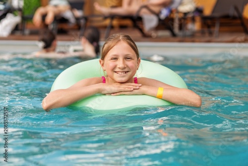 Smiling child relaxing in swimming pool with inflatable ring during vacation