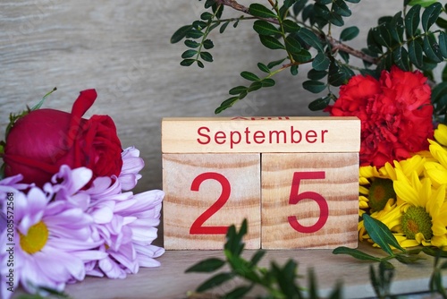 September 25, wooden calendar with fresh, colorful flowers.