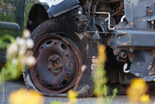 Close up of a wrecked car wheel and exposed front suspension after a serious road collision