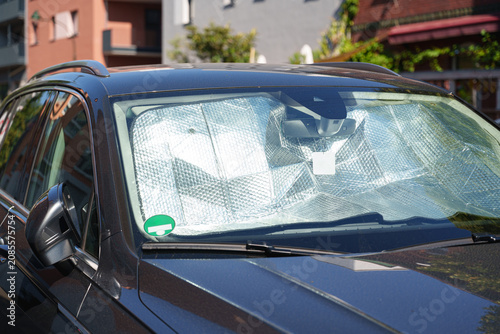 Parked SUV with reflective windshield sunshade protecting the cabin from summer heat