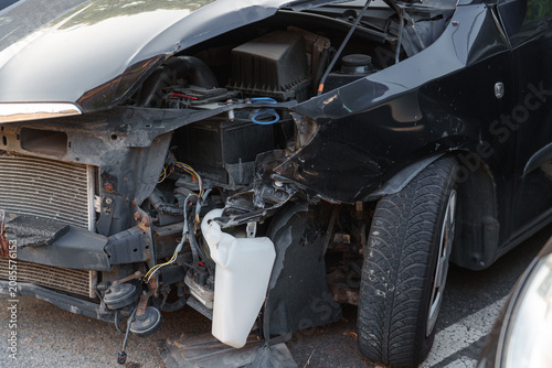 Close view of a damaged black car front revealing internal components after a collision