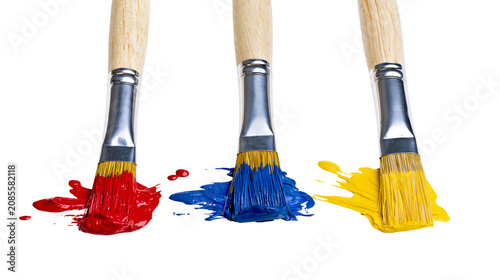 Photos Three paint brushes with red blue, and yellow paint splatters