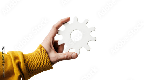 Hand holding white gear cog with yellow sweater sleeve