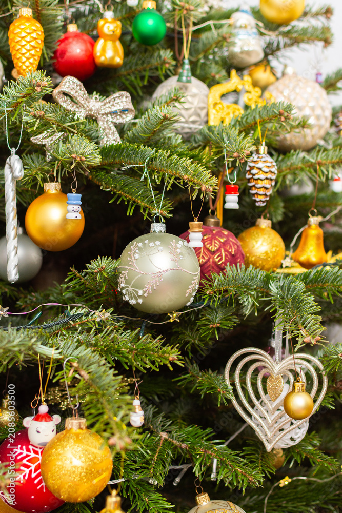 Obraz premium A Christmas tree stands with many colorful ornaments hanging from its branches. Each ornament shows different shapes and colors, celebrating the festive season and bringing joy to the home.