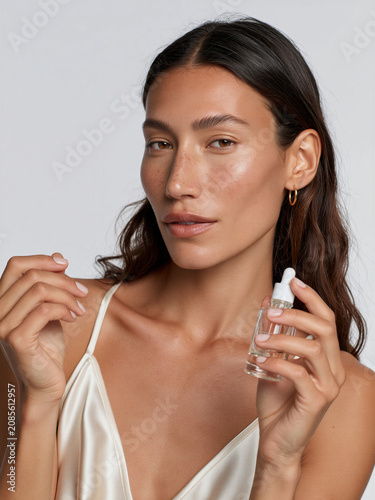 Woman holding a skincare serum bottle during a morning ritual