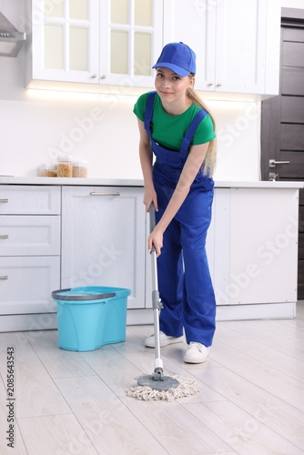 Fotografie Teenage worker mopping floor in kitchen. Part-time job