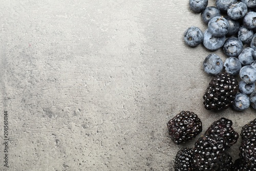 Canvas Print Fresh ripe blackberries and blueberries on grey table, flat lay