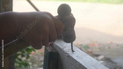 A small child's hand is holding a hammer to nail a wooden board.