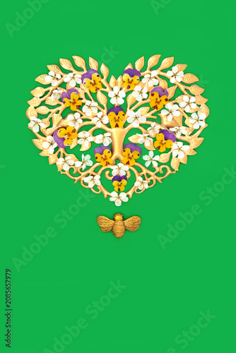 Gold heart tree shape decoration, blossom, pansy flowers with bee ornament on green background.
