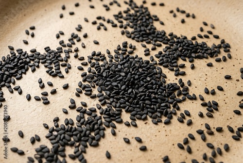 Macro shot of black sesame seeds scattered on a textured ceramic surface