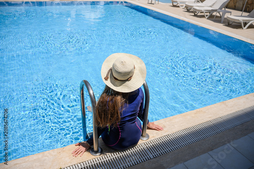 Photography Rear view of female tourist wearing protective long sleeve swimwear and sun hat