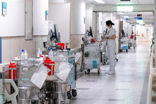 Photos A nurse pushes a medical trolley through a bright hospital corridor, transporting medications and clinical supplies for patient care