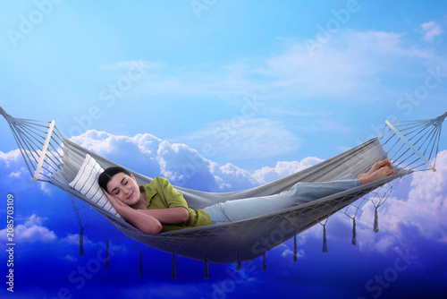 Foto Young woman sleeping in hammock against bright sky