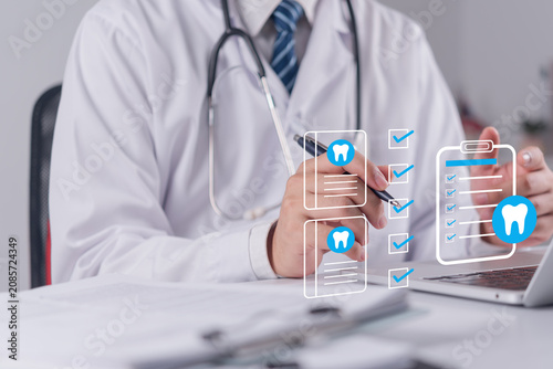 Dentist hands using laptop with digital dental checkup checklist hologram concept for oral healthcare clinic management dental insurance and modern dentistry technology