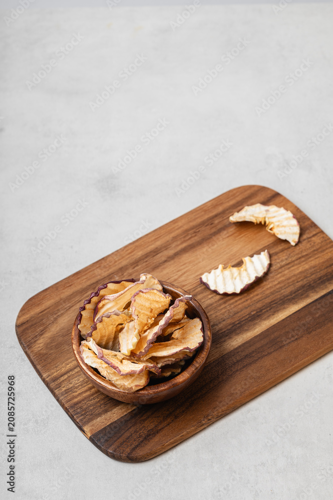 Fototapeta premium Apple chips in a wooden bowl on a light gray background.