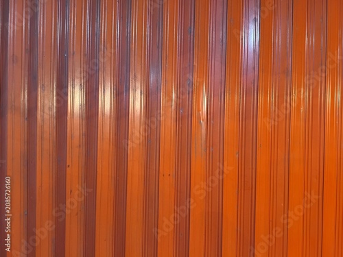 Orange corrugated metal gate texture background, industrial surface, vertical lines, weathered paint