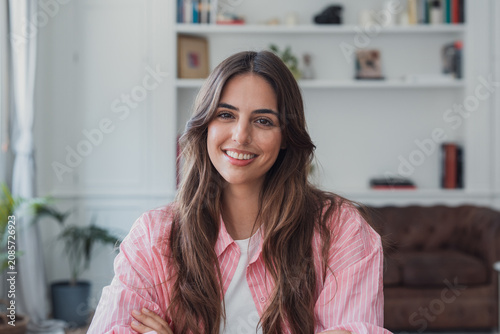 Obraz na płótnie Young woman with long brown hair smiling confidently and looking directly at the