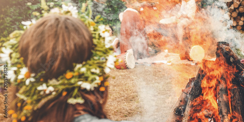 Close-up of a woman wearing a wildflower wreath by the sacred solstice fire.