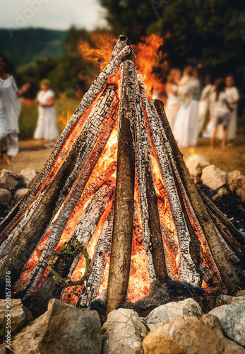 Ceremonial throwing of a wildflower wreath into the sacred solstice fire.