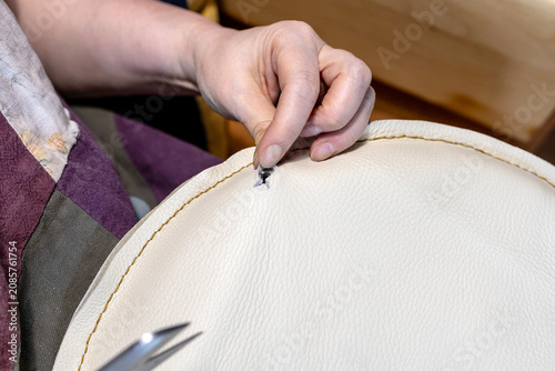 Schilderij op canvas craftswoman sews up hole in leather seat of chair