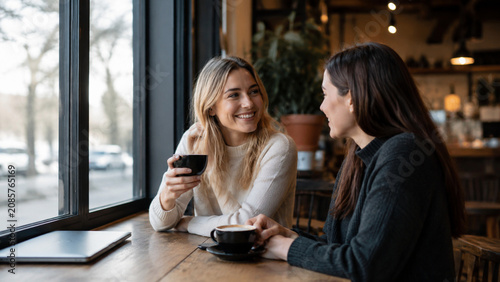 Two Friends Talking Beside Cafe Window with Laptop