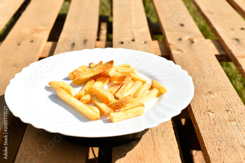 French fries on white plate on wooden background, junk food. 