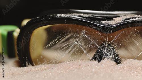 Worn safety goggles scratched lens sand particles dust protective eyewear closeup texture plastic workshop