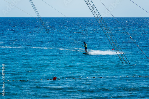 Canvas Print Wakeboarder gliding across crystal-clear seawater using cable wakeboarding system