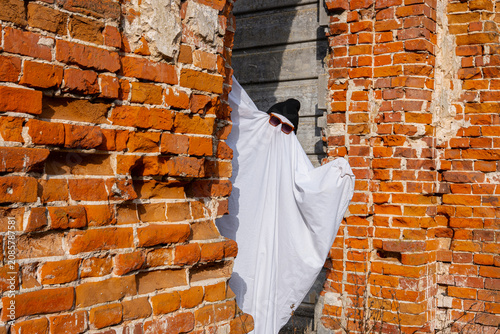 Ghostly figure in Halloween costume by brick wall