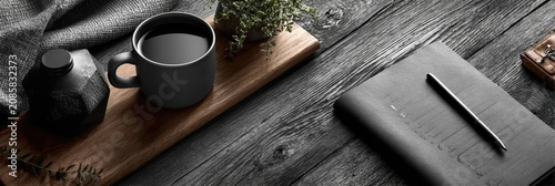 Cozy workspace on a dark rustic wooden table, featuring a mug of coffee, a notebook, and a pen, creating a calm and contemplative atmosphere for journaling or studying
