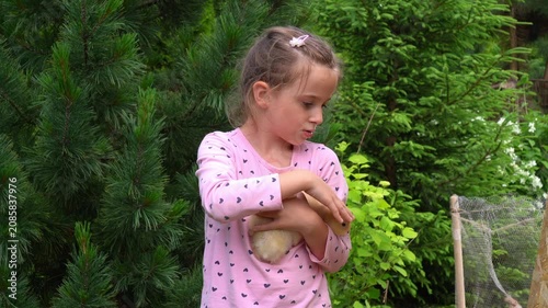 Happy girl hold yellow little duckling in garden in countryside. Children care pets. Kids play with animals. Poultry, agriculture, farming. Subsistence farming