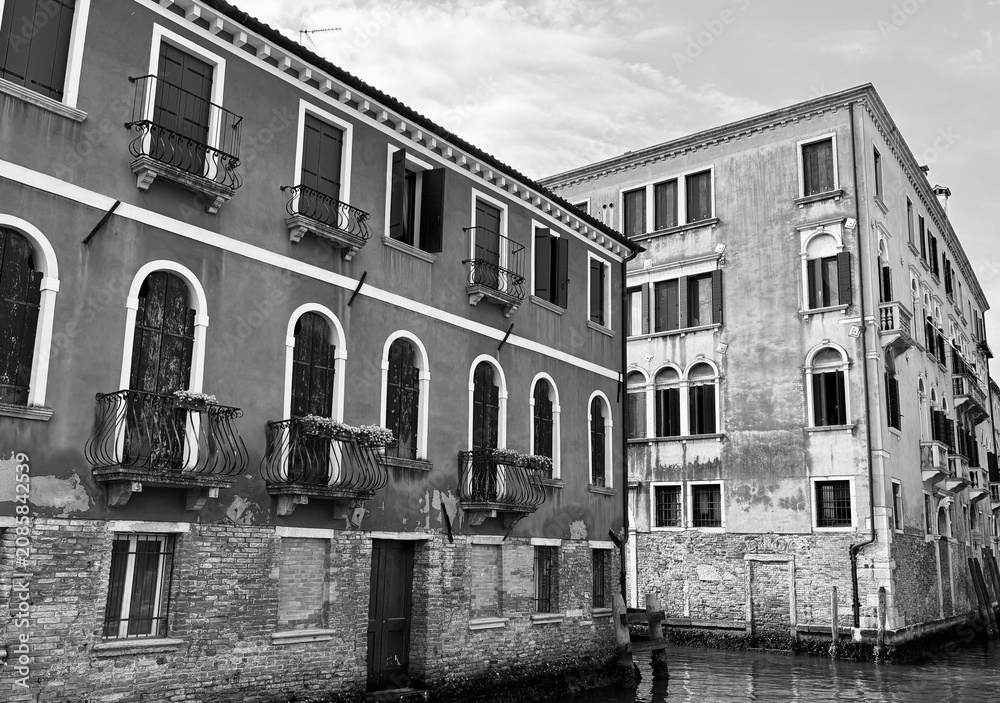 Naklejka premium Historic Venetian palaces along a quiet canal, black and white, Venice