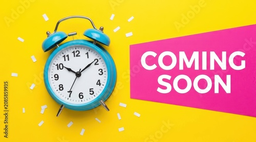 Blue vintage alarm clock on yellow background with pink coming soon sign for marketing announcement and news.