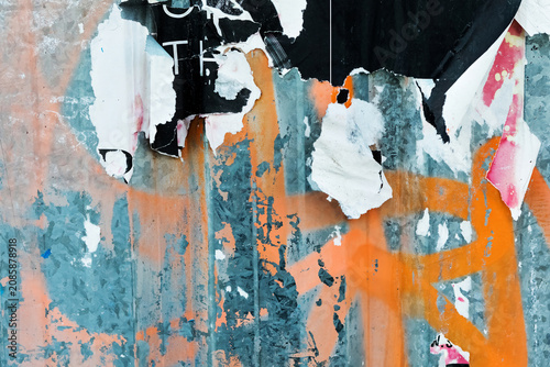 Torn street poster, peeling off a wall background with graffiti