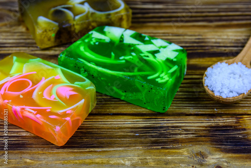 Pieces of the handmade soap and spoon with sea salt on wooden background