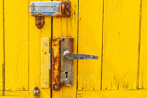 Cuadro en lienzo Dilapidated colourful yellow wooden beach hut door with a handle on the beach in