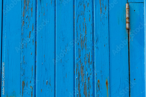 Fotografi Weathered blue board of a traditional British beach hut with a hinge as the pain