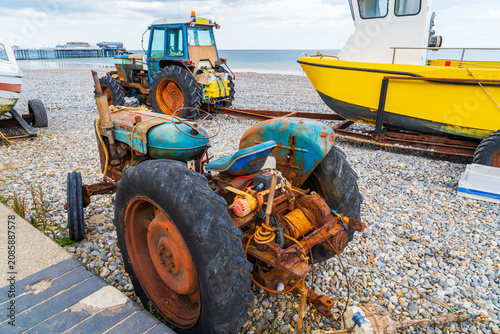 Fishing boat and tractors on the pebble beach in Cromer, North Norfolk UK