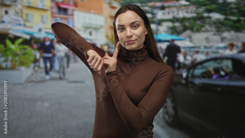 Photos Young woman pinching nose and holding hand to nostrils on busy street market in brown turtleneck; disgust urban discomfort irritation