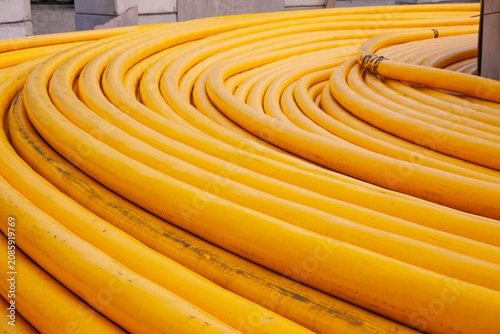 Close up view of bright yellow heavy duty underwater subsea power electric cables coiled at a port industrial terminal