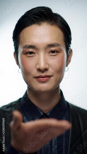 Well-groomed professional person with thoughtful gaze, then confident smile & open-handed gesture, against pristine white-grey gradient. Soft lighting. Concept of professional insight and solution