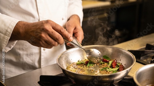 Indian chef tempering spices, Mustard cumin curry leaves, Hot oil pan close up, Classic tadka technique, Warm restaurant kitchen