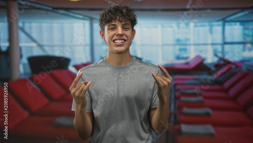 фотографія Teenager makes rock sign with hands in airport lounge with red recliners; youthful playful confidence