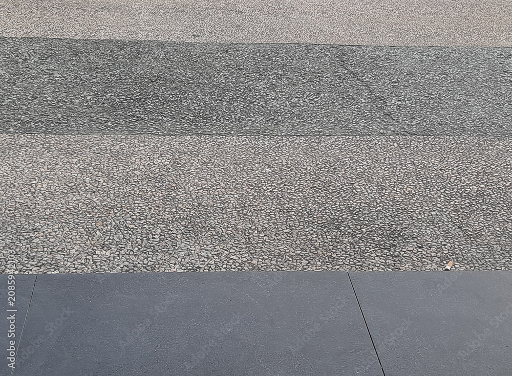 Fototapeta premium Contrast Between Rough Textured Gravel and Smooth Dark Grey Stone Floor Tiles
