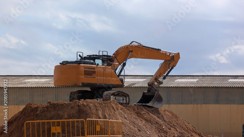 Fotografía Crawler excavator positioned on earth embankment at industrial redevelopment construction site