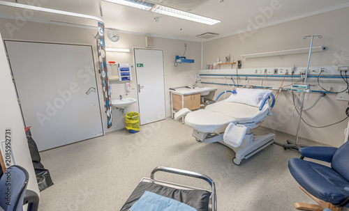 Empty hospital delivery room with medical bed and equipment.