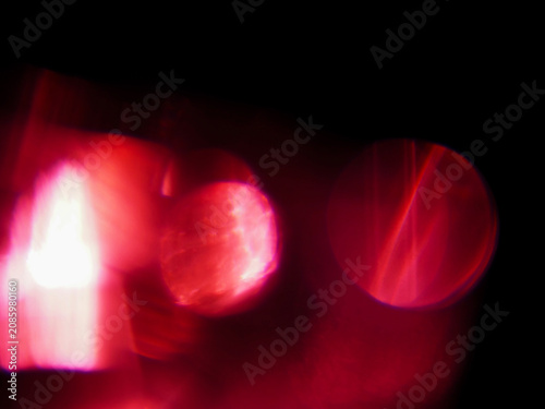 Abstract red light leaks with glowing red light streaks against dark background. Visual effect created by camera movement or light trails. Graphic background for design.