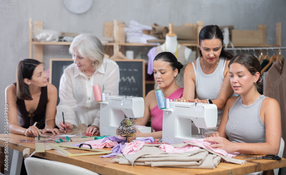 Obraz premium Busy women of different ages sewing and drawing with teacher at dressmaking class